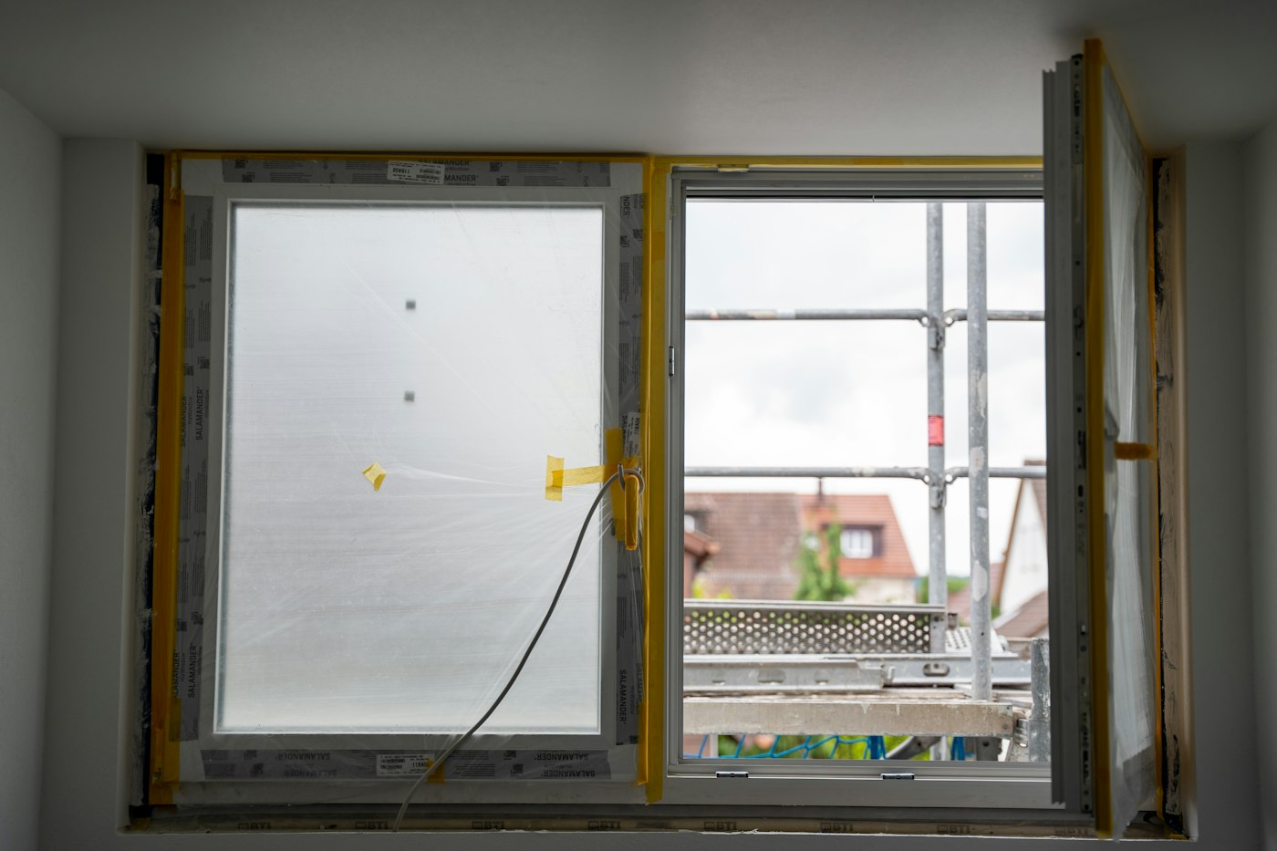 Neue Fenster während des Einbaus, mit Klebeband und Schutzfolie