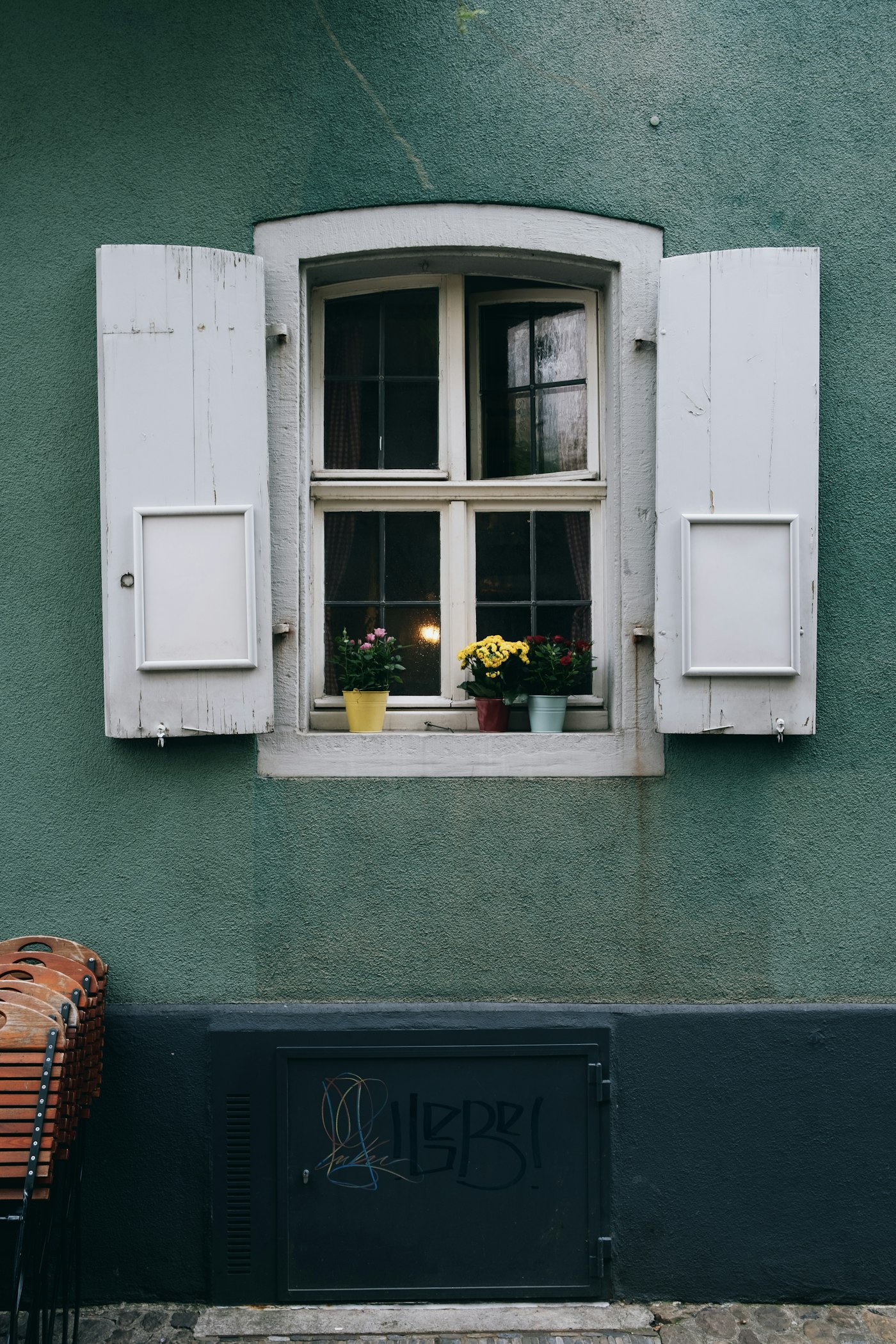 Altbaufenster mit weißen Klappläden an grüner Fassade
